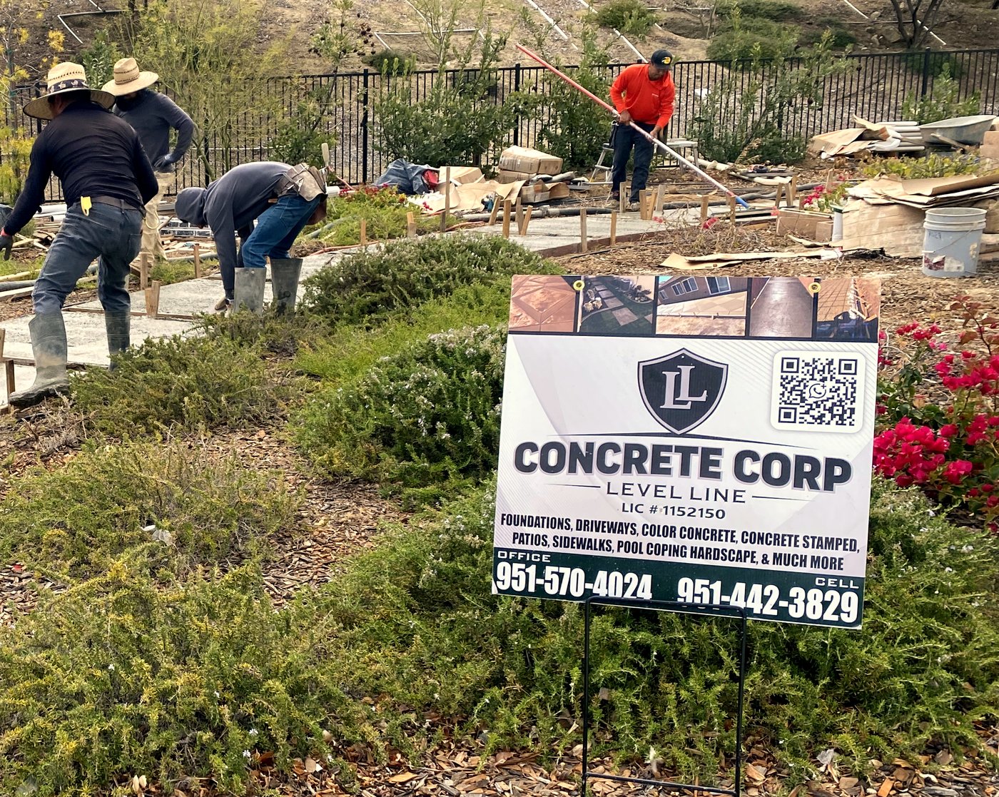 The Level Line crew finishing a concrete walkway on a job site, with the company's licensed sign posted
