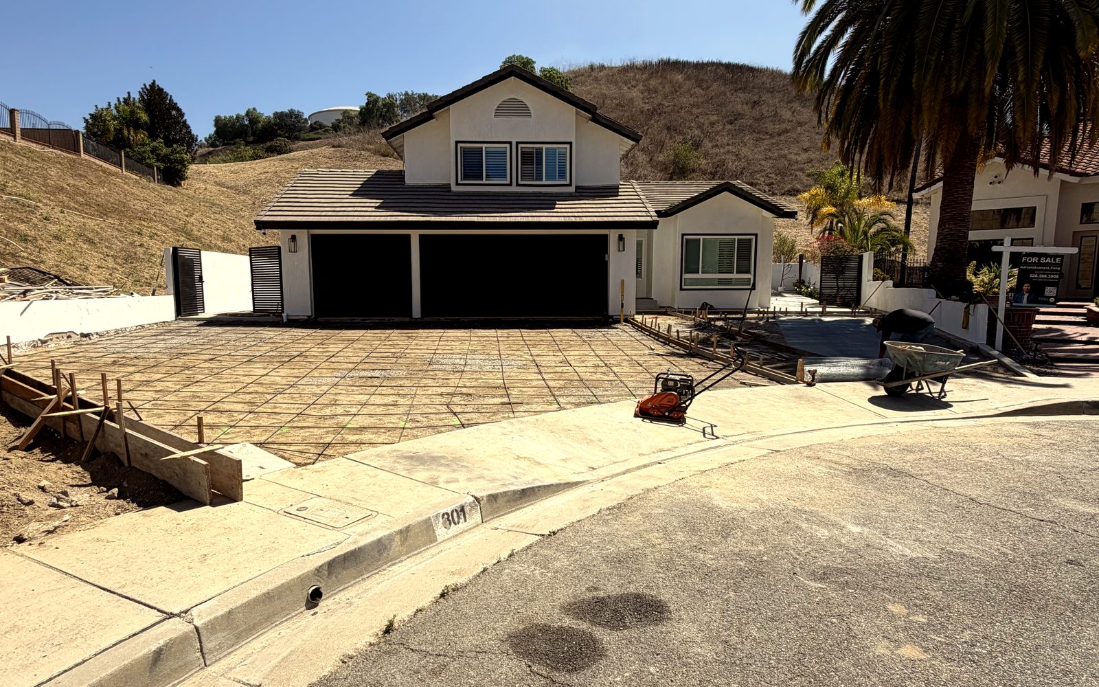 Hillside home before the pour: graded dirt driveway staked with wood forms