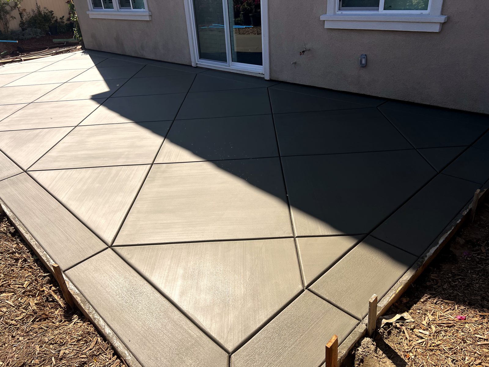 Finished diamond-scored gray concrete patio outside sliding glass doors