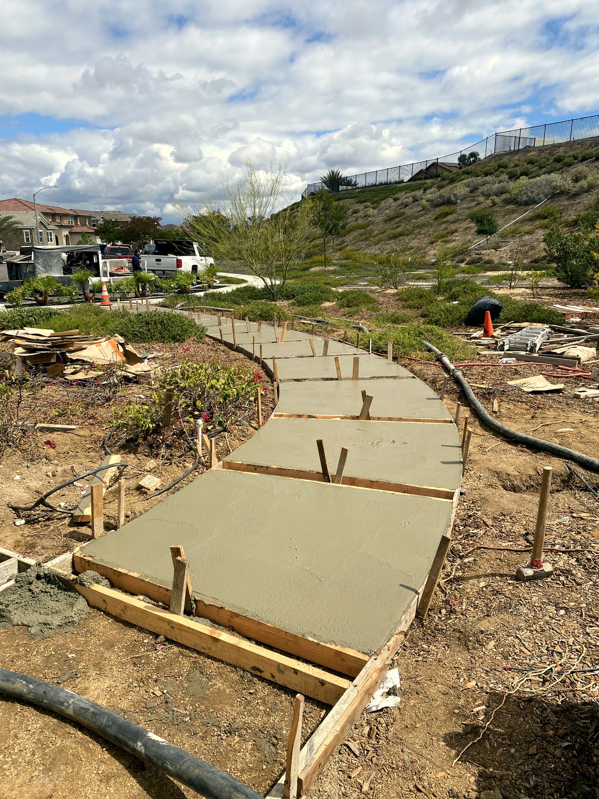 Wood forms staked out for a curved concrete walkway, freshly poured and ready to finish