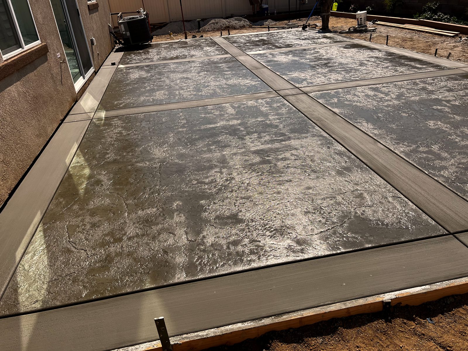 Freshly poured backyard patio still wet in the forms, with smooth troweled borders